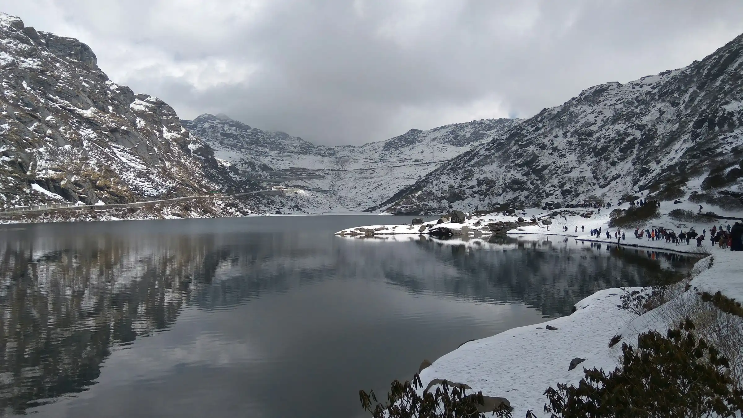 Tsomgo Lake in winter, its still water mirroring snowy slopes